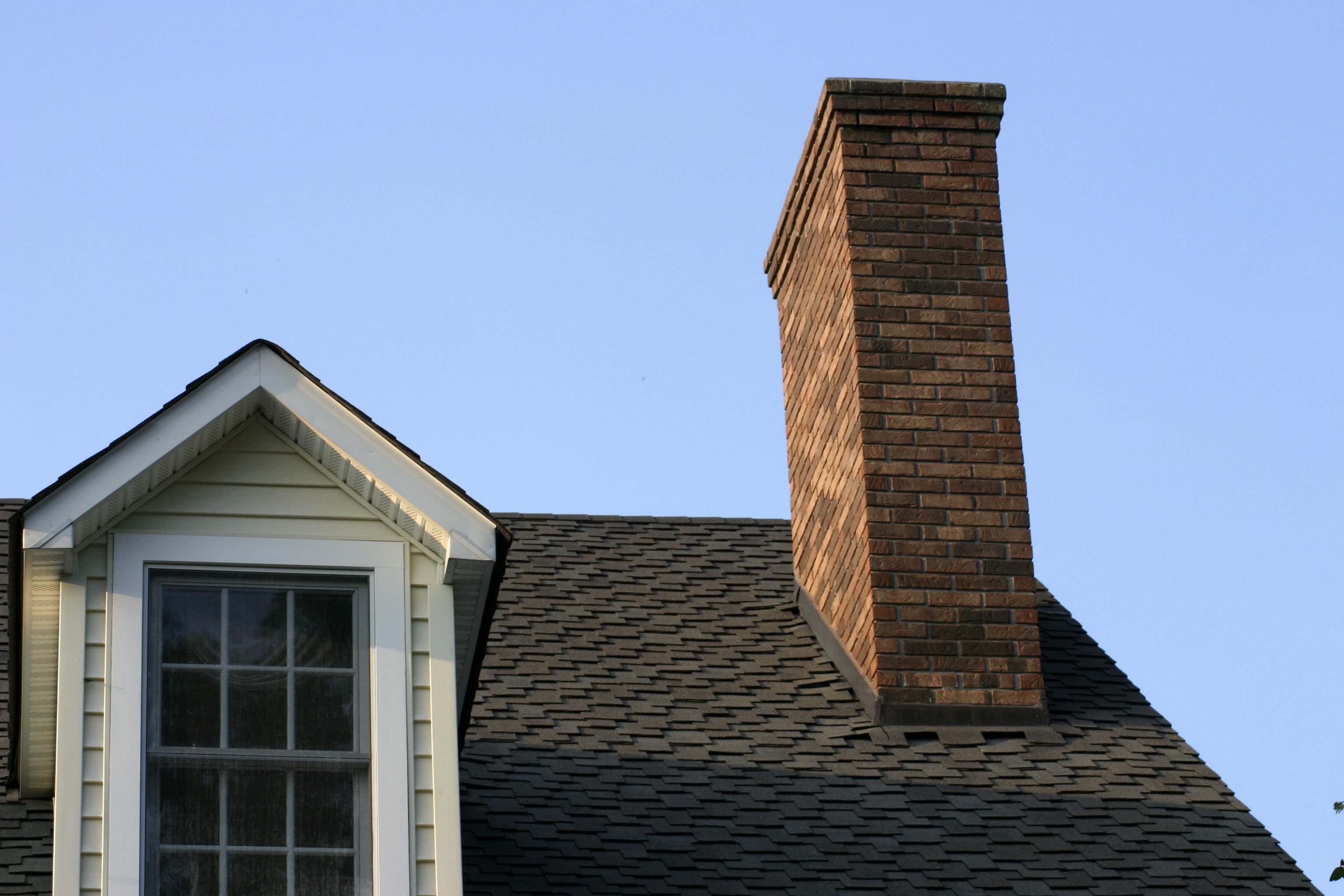 traditional house with siding, shingles, and brick chimney